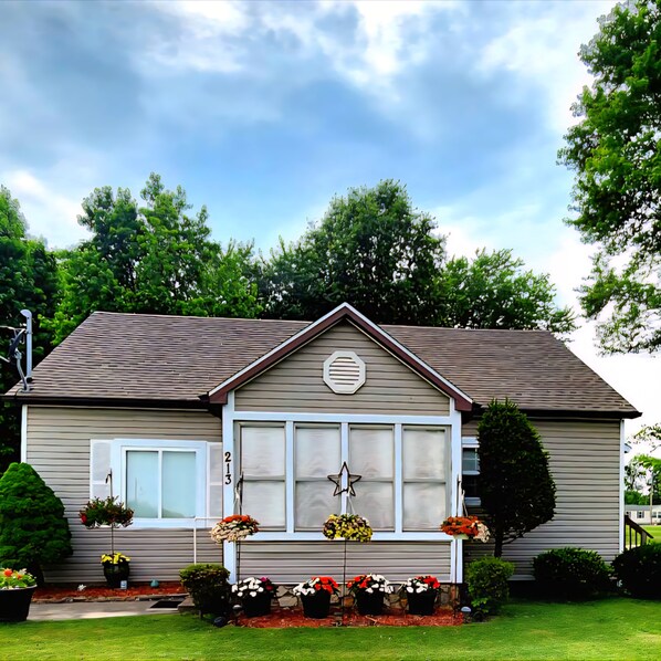 A single-story house with a gabled roof, a front porch with a star decoration, and a number '213' on the wall.