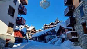 Un village enneigé, avec ses bâtiments traditionnels en bois, ses murs de pierre et ses balcons.