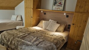 Une chambre confortable avec une tête de lit en bois, un plaid moelleux en fausse fourrure et un tableau encadré au mur.