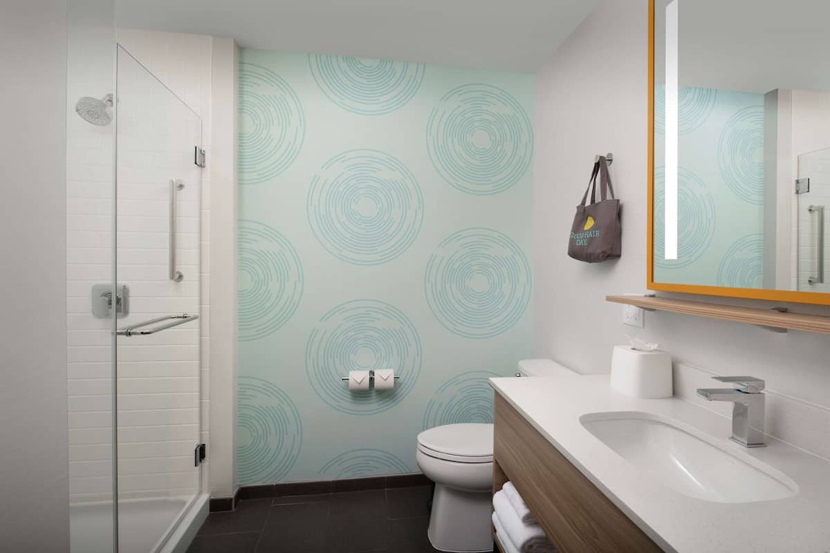 Een moderne badkamer met een douchecabine van glas, een toilet en een wastafel met een houten meubel.