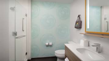 A modern bathroom with a glass shower enclosure, a toilet, and a sink with a wooden vanity.
