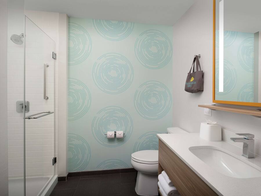 A modern bathroom with a glass shower enclosure, a toilet, and a sink with a wooden vanity.
