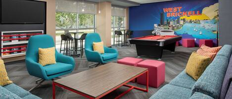 Un espace de détente moderne, doté de sièges confortables, d’une table de billard et d’une fresque représentant West Brickell.
