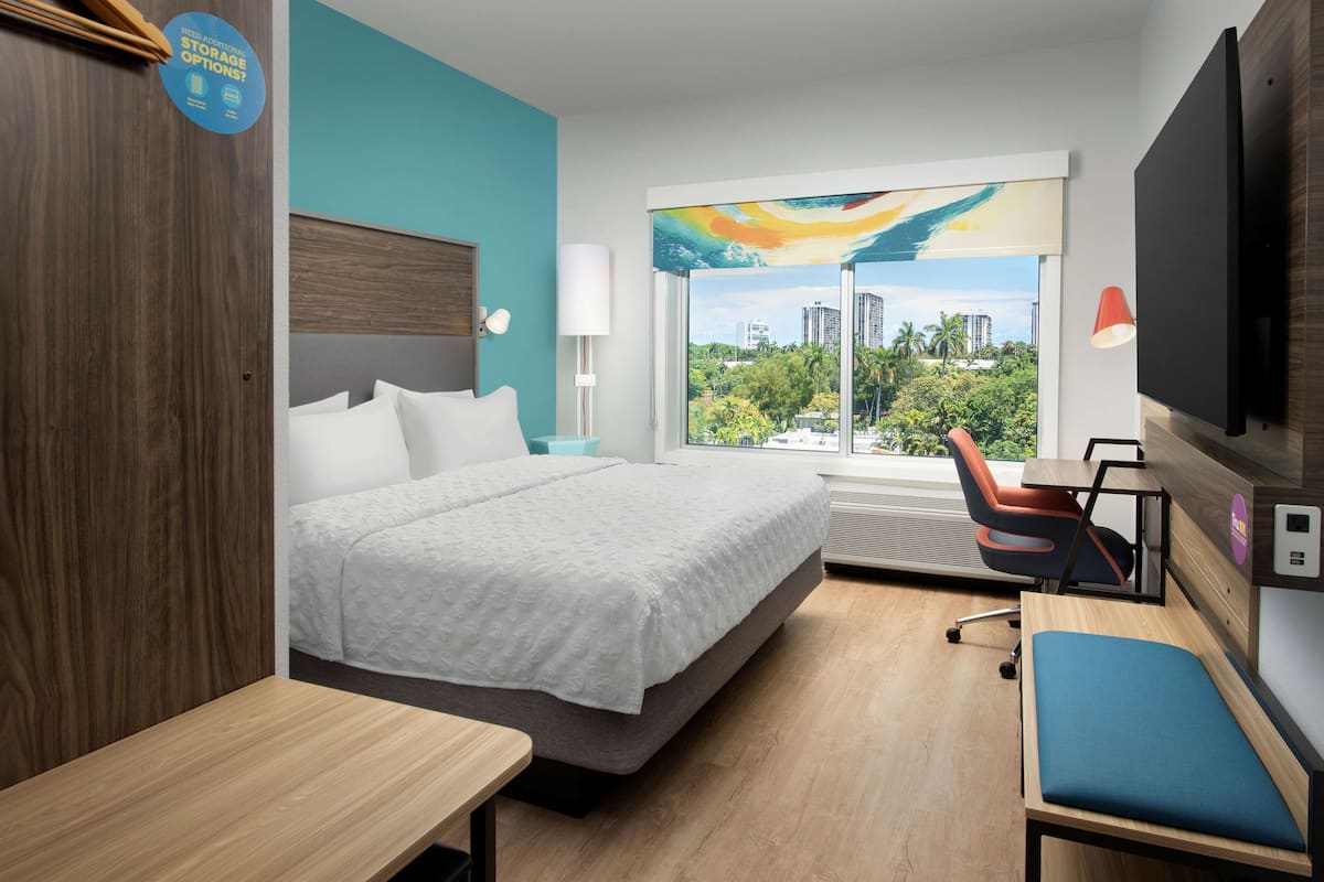Hotelkamer met een bed, bureau, stoel, televisie en raam met uitzicht over de stad.