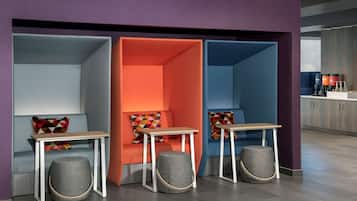A modern interior with three seating areas, each with a table and ottoman, and a kitchen area in the background.
