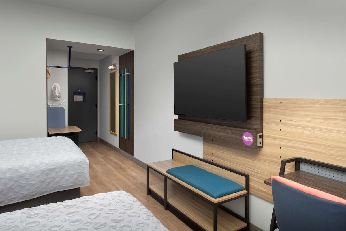 Een hotelkamer met twee bedden, een televisie, een bureau en een bank.
