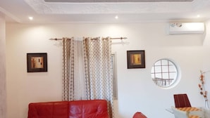A living room with a red leather sofa, a glass coffee table, and a round mirror on the wall. - Lovely 2-bed Apartment in Kribi-douala (Kribi)