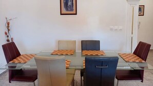 A dining area with a glass table, four chairs, and chessboards. - Lovely 2-bed Apartment in Kribi-douala (Kribi)