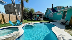 A swimming pool with a hot tub, surrounded by a concrete deck and a wooden fence. - 12-Bedroom Home with Private Pool & Large Yard, About Half Mile to Beach (Galveston)