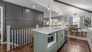 A kitchen with a central island, wooden flooring, and pendant lighting. - Hot Tub | Great Location | King Beds | Grill & Patio (Lexington)