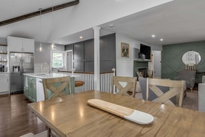 A modern kitchen with a dining area, wooden chairs, and a fireplace. - Hot Tub | Great Location | King Beds | Grill & Patio (Lexington)