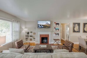 Una sala de estar con chimenea, televisor y obras de arte en las paredes.