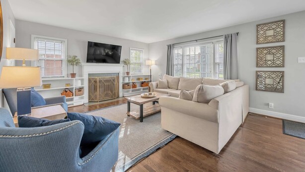 Una sala de estar con un sofá, sillones, una mesa de centro, chimenea y televisor.