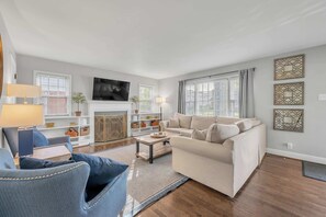 A living room with a sofa, armchairs, a coffee table, a fireplace, and a TV. - Updated Home | Downtown | Luxe Beds | Ping Pong (Lexington)
