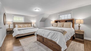 Un dormitorio con dos camas, una lámpara de techo, una ventana y una mesita de noche con una lámpara.