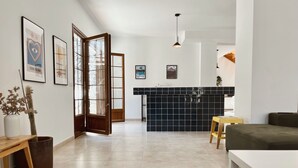 A modern kitchen with black tiles, a wooden dining table, and a sofa. - Casa Moci (Playa Blanca)