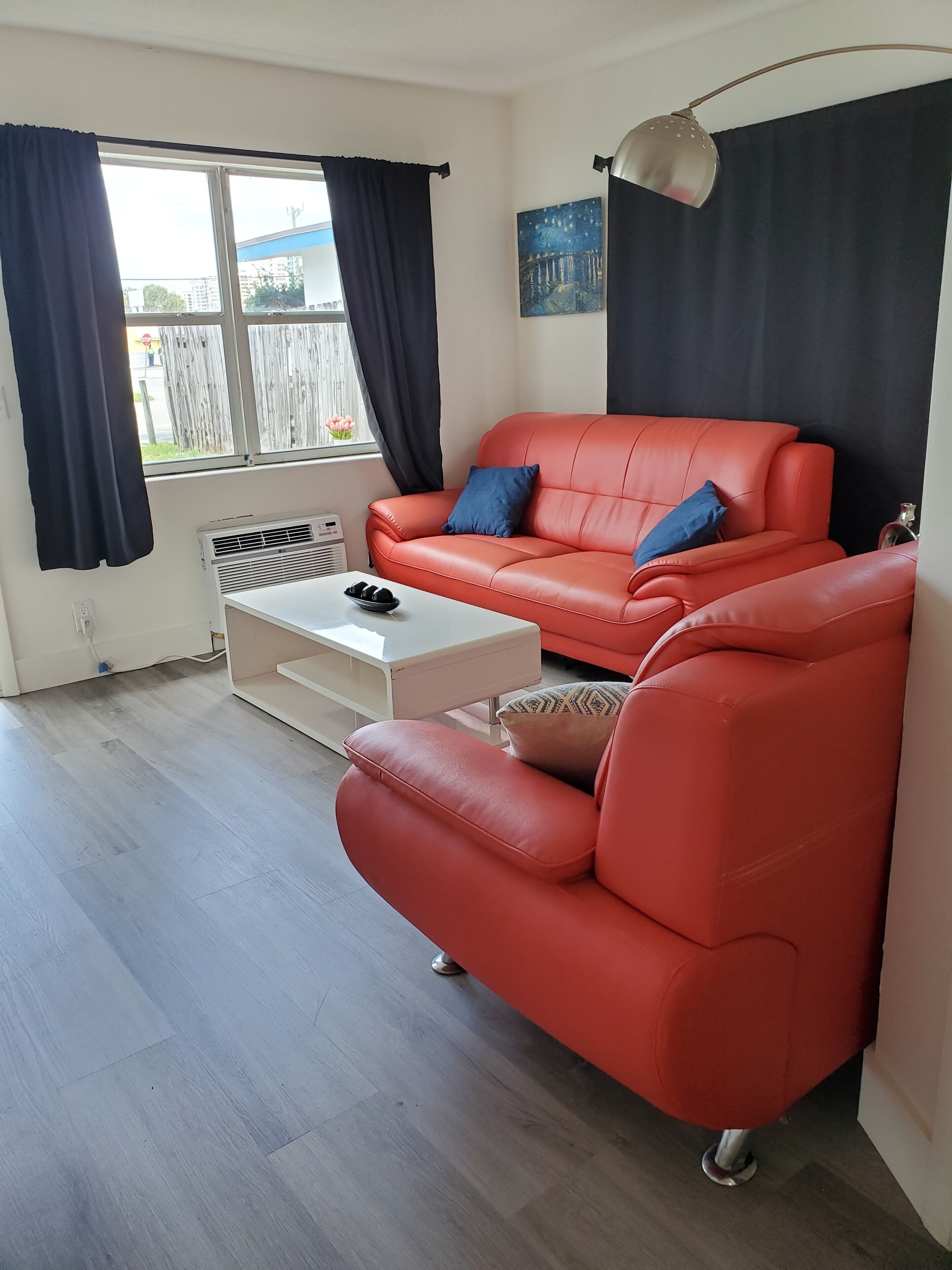 A living room with a red sofa, a white coffee table, and a painting on the wall.
