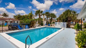 A rectangular swimming pool with a 4 FT depth marker, surrounded by a white deck, blue chairs, and palm trees. - ☼☼ Walk 2 the Beach ~♡♡~ Gorgeous 1 BR ☼☼ (West Palm Beach)
