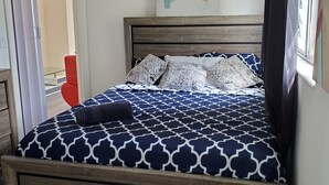 A bed with a patterned bedspread, a wooden headboard, and a wall-mounted abstract painting. - ☼☼ Walk 2 the Beach ~♡♡~ Gorgeous 1 BR ☼☼ (West Palm Beach)