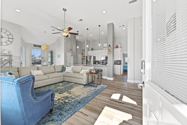 A modern living room with a sectional sofa, a blue armchair, and a wooden coffee table. - Game Room-Beach Views-Incredible Breeze-Sleeps 14- Child Friendly (Bolivar Peninsula)