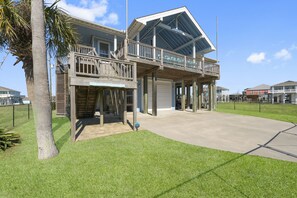 A two-story house with a balcony, a garage, and a well-maintained lawn. - Game Room-Beach Views-Incredible Breeze-Sleeps 14- Child Friendly (Bolivar Peninsula)