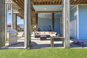 An outdoor patio area with a sofa, a table, and a grill. - Game Room-Beach Views-Incredible Breeze-Sleeps 14- Child Friendly (Bolivar Peninsula)