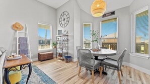 A dining area with a round table, grey wicker chairs, a clock on the wall, and a sign reading "OCEAN".