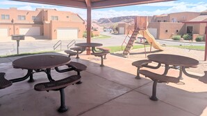 A covered patio with picnic tables and a playground. - Beautiful Moab Townhome (moab)