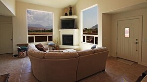 A living room with a large sectional sofa, a fireplace, and large windows offering a mountain view. - Beautiful Moab Townhome (moab)