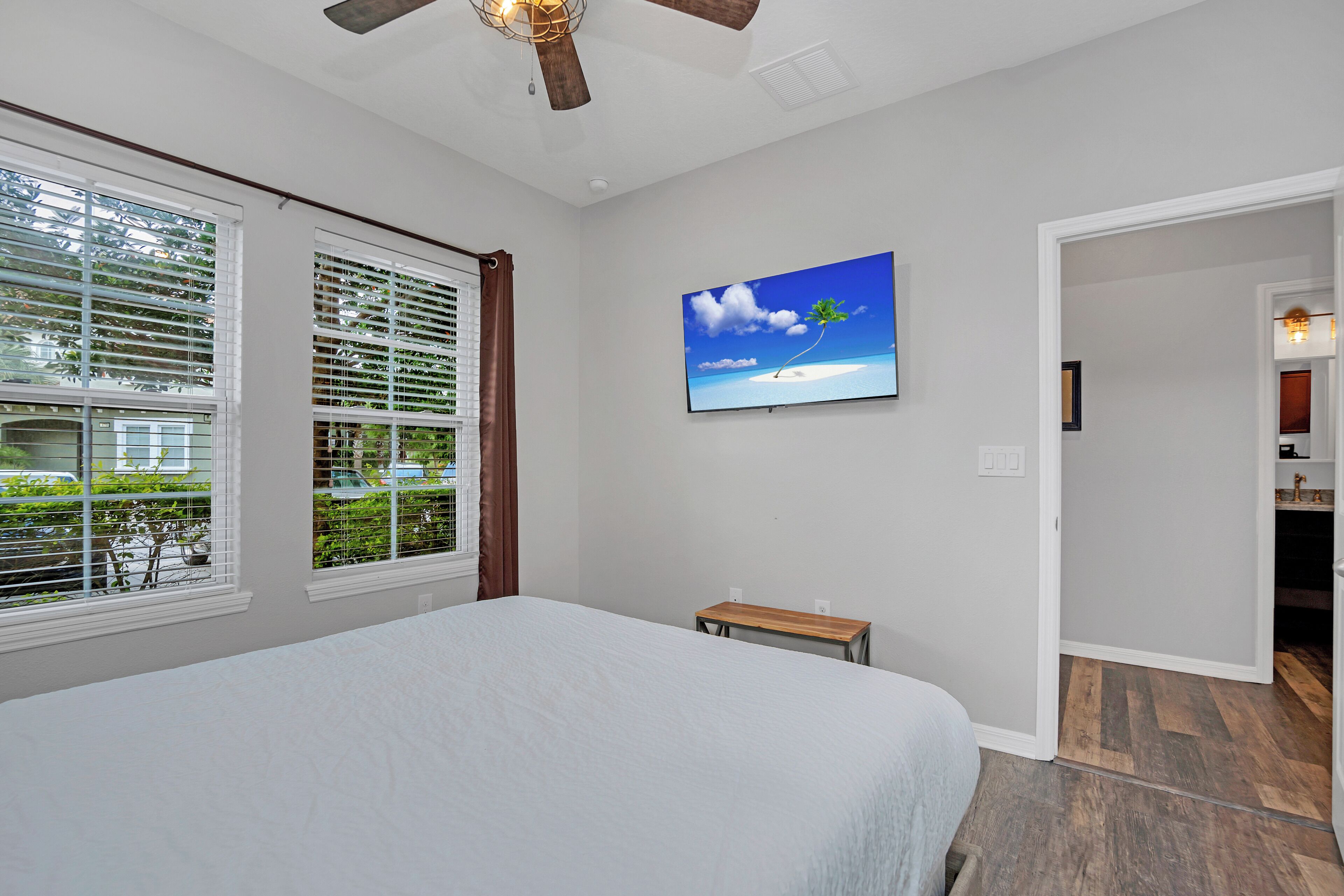 A bedroom with a bed, a TV on the wall, and a view of the outside.