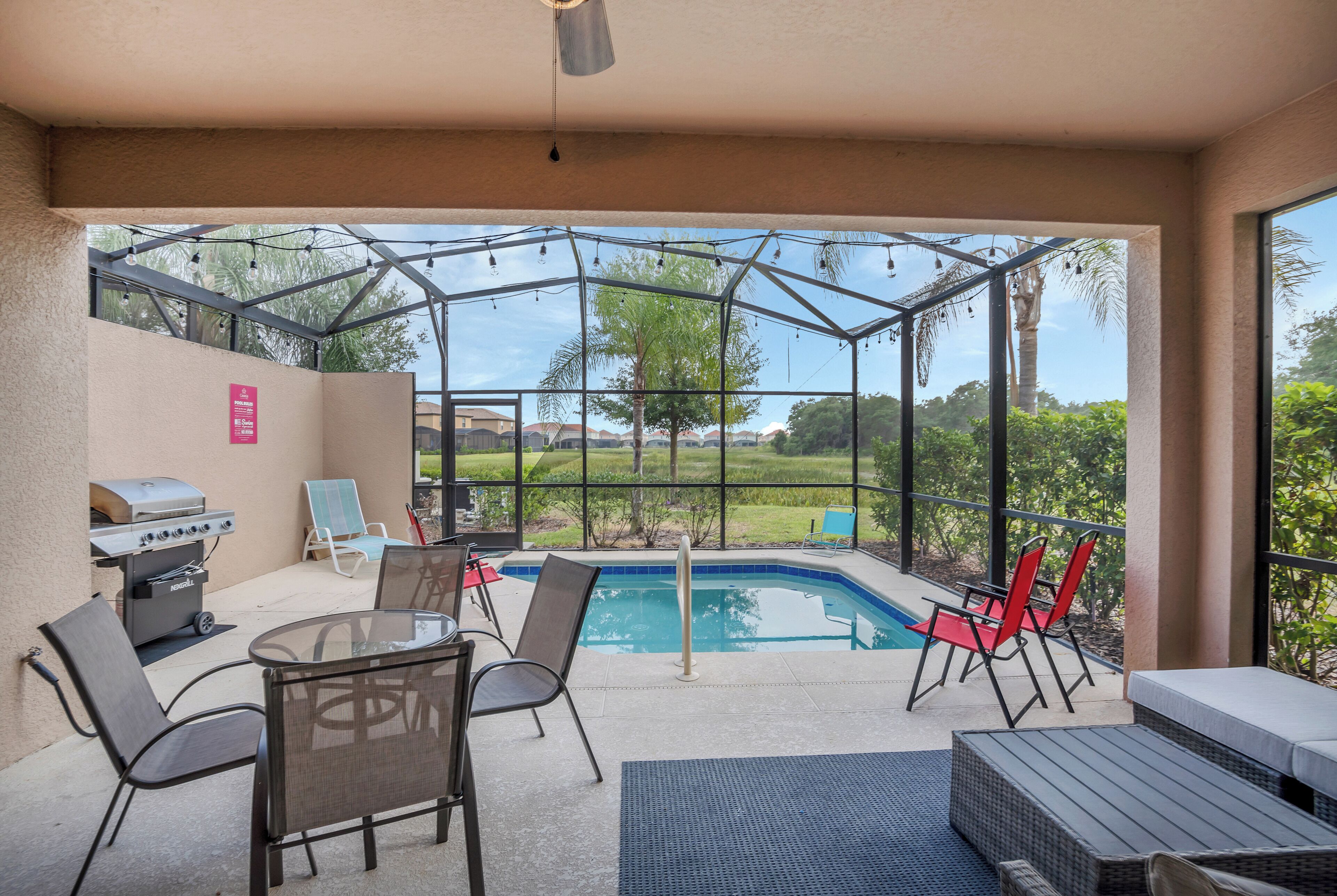 A covered patio with a pool, outdoor furniture, and a grill.
