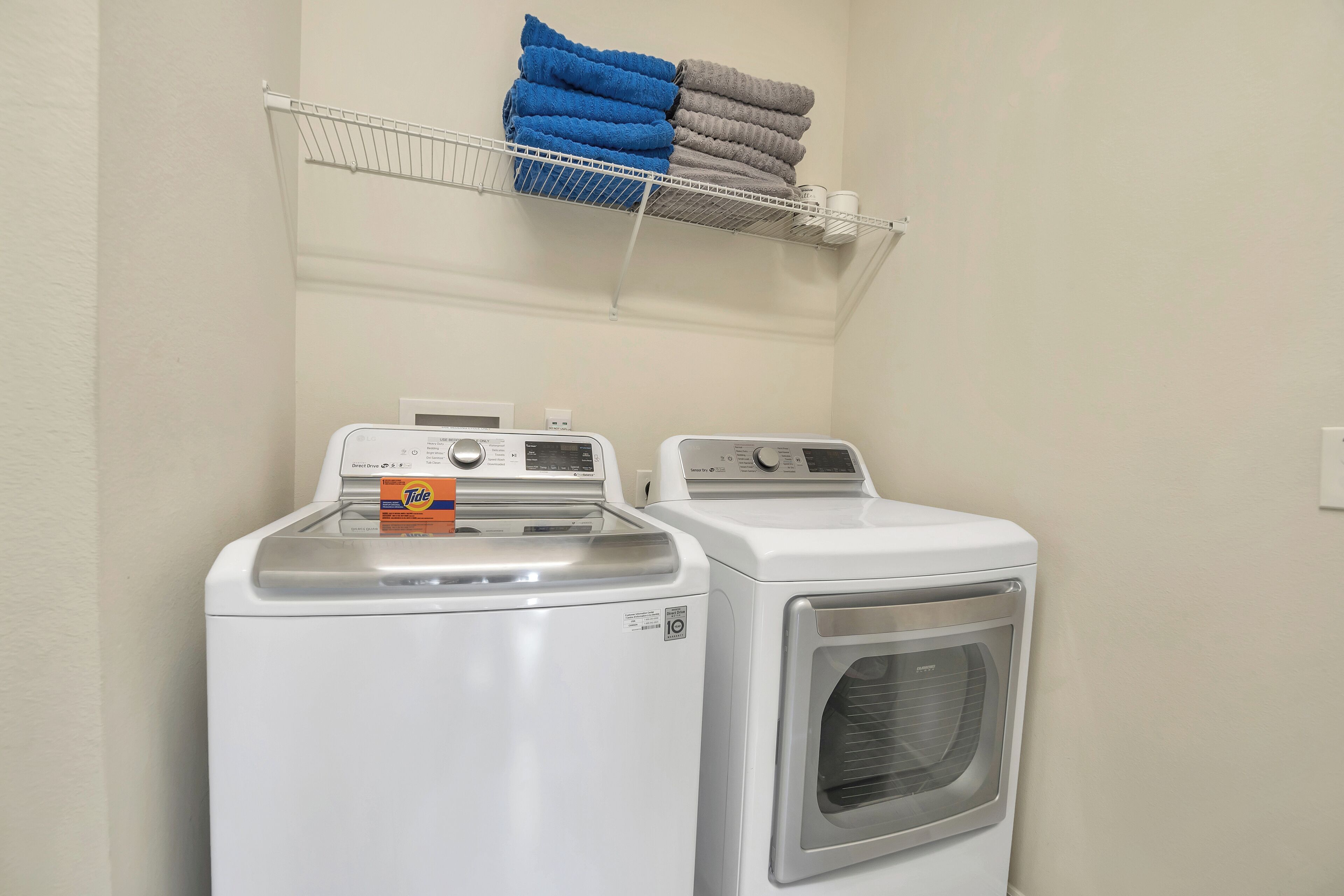A laundry area with two front-loading washing machines and a drying rack above.