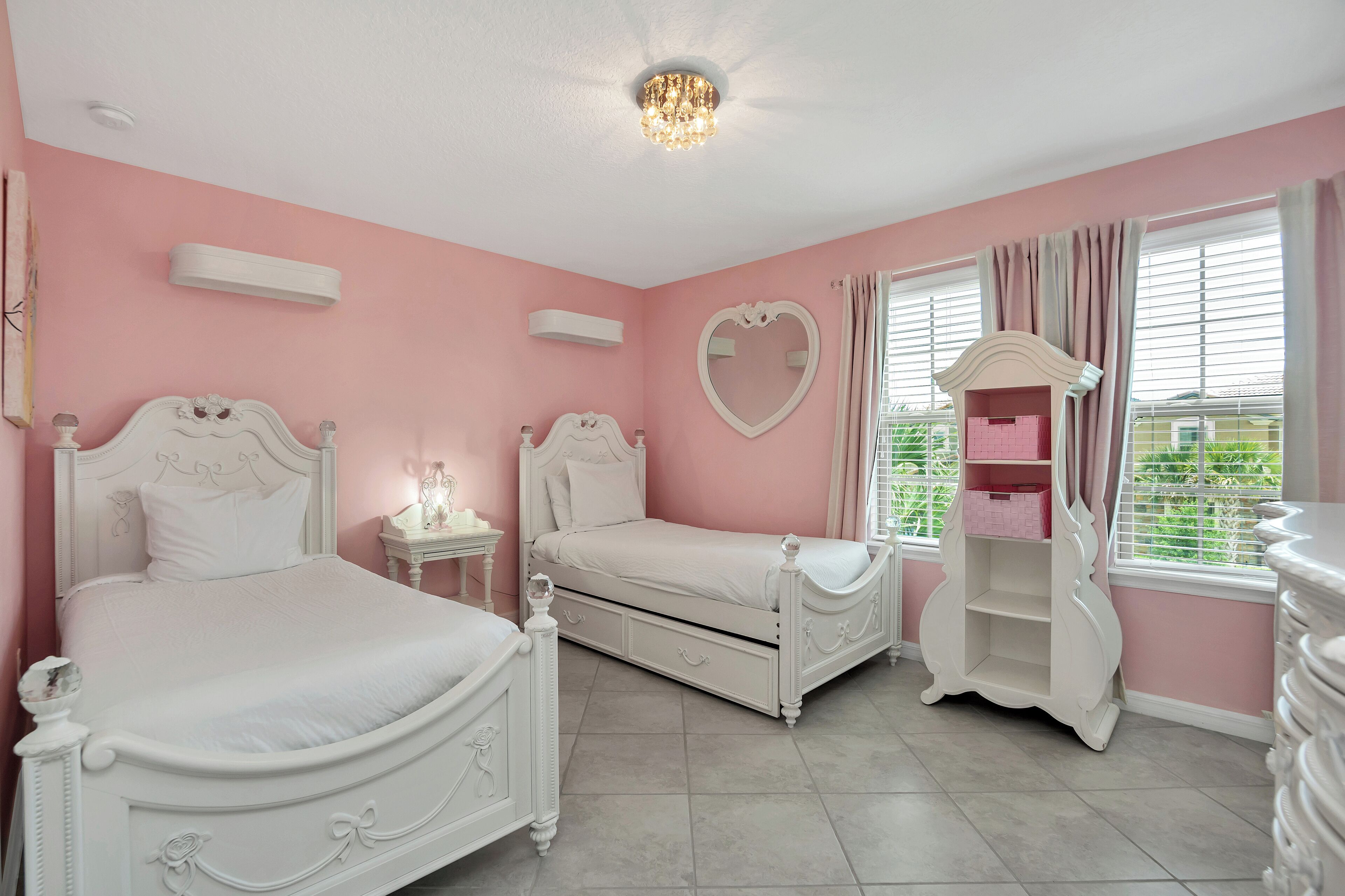 A bedroom with two white beds, a heart-shaped mirror, and a dresser.