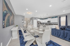 Relax in this stylish living space with a dining area, featuring a glass-top table and comfortable seating.