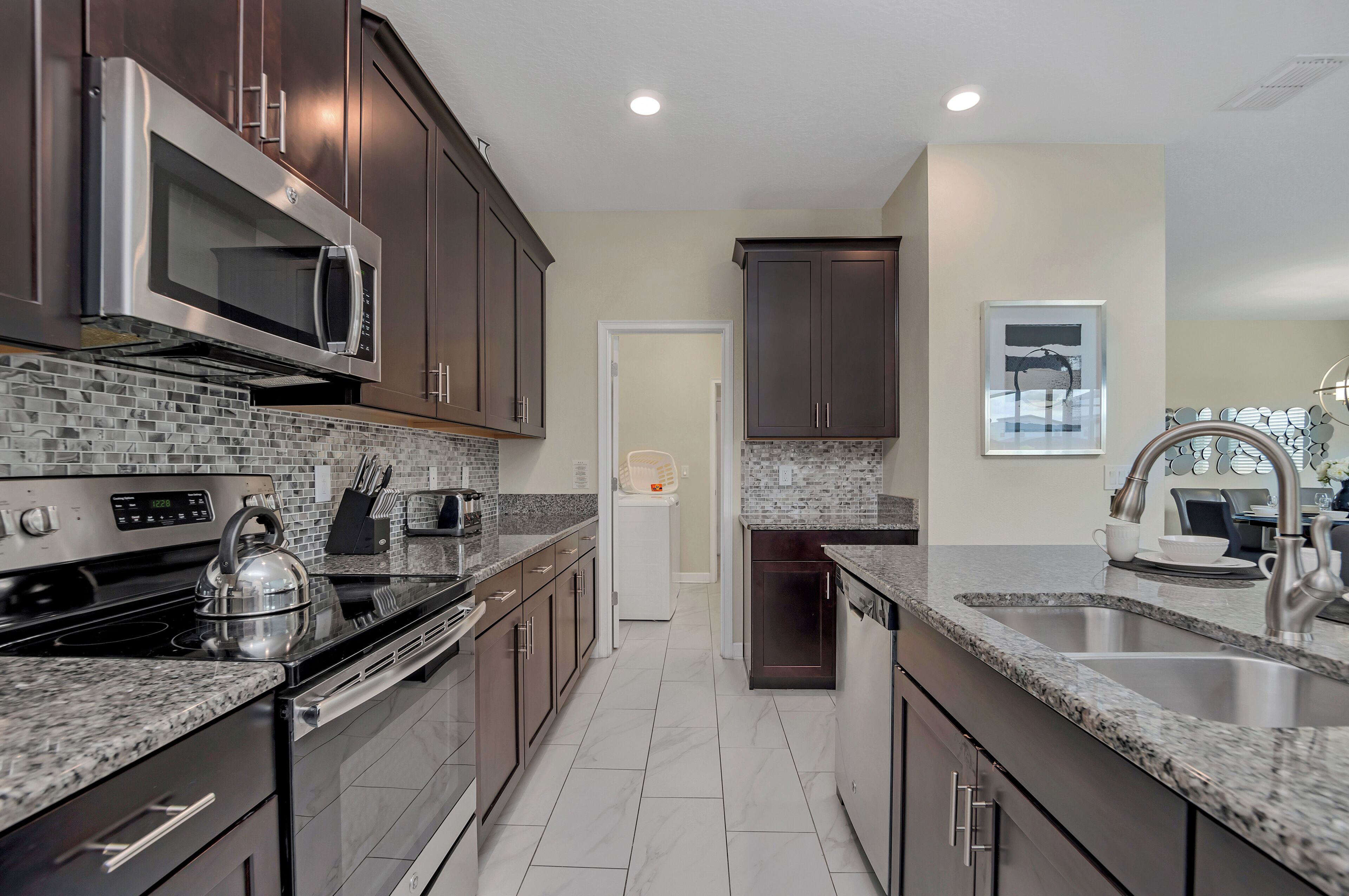 A modern kitchen with dark wood cabinets, stainless steel appliances, and a tiled backsplash.