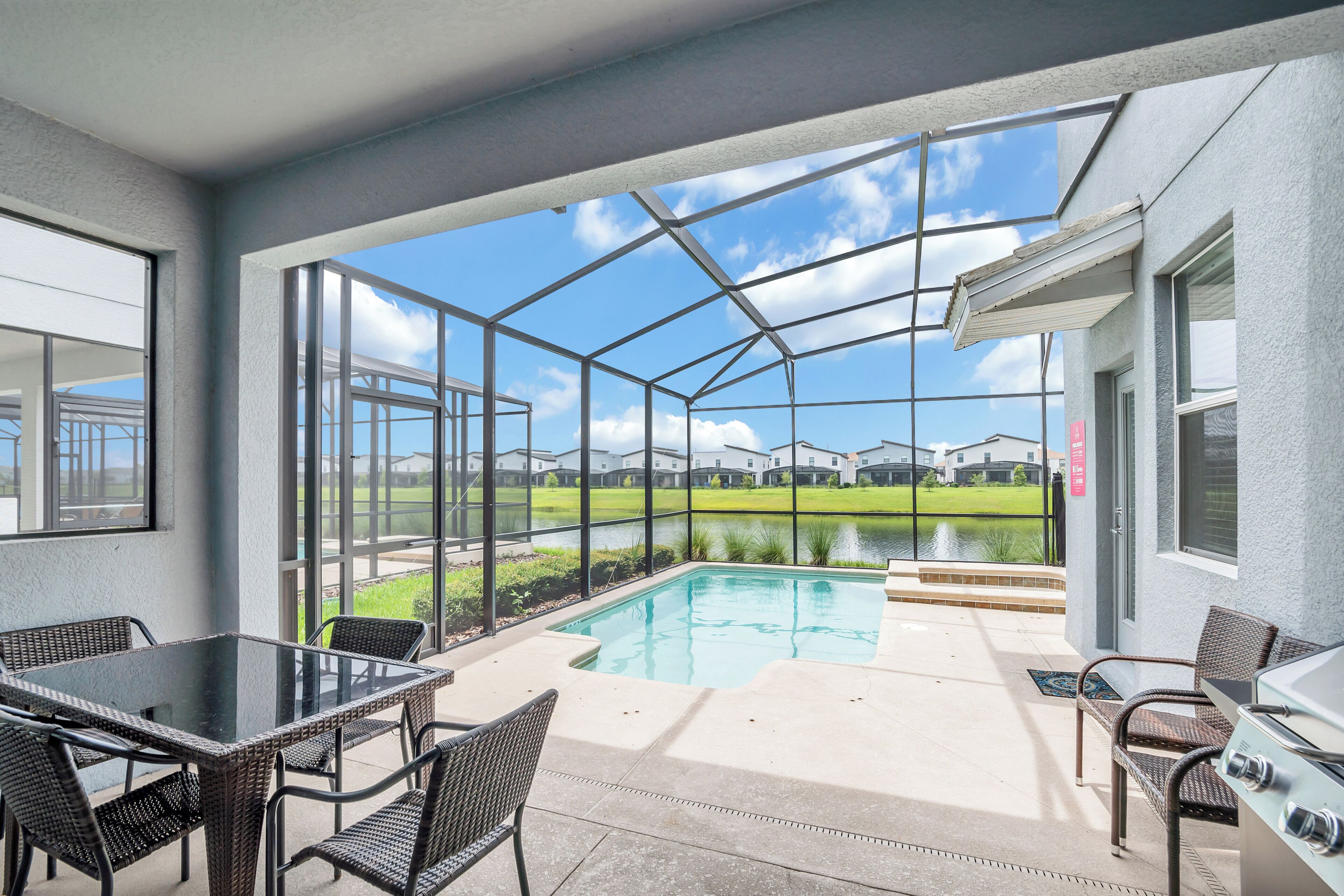 A covered patio with a glass enclosure, a pool, and outdoor furniture.