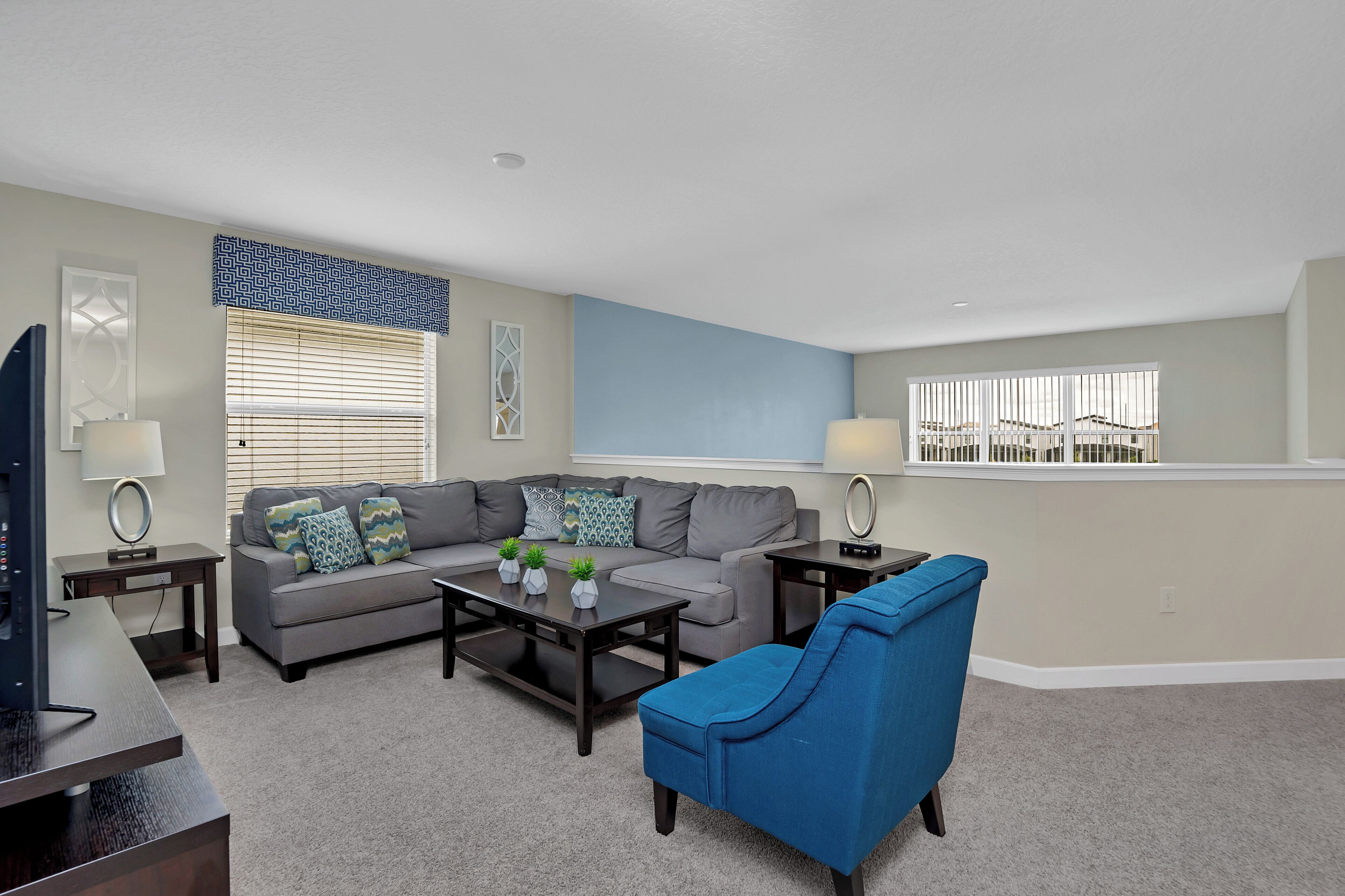A living room with a gray sofa, blue armchair, and a coffee table with decorative items.