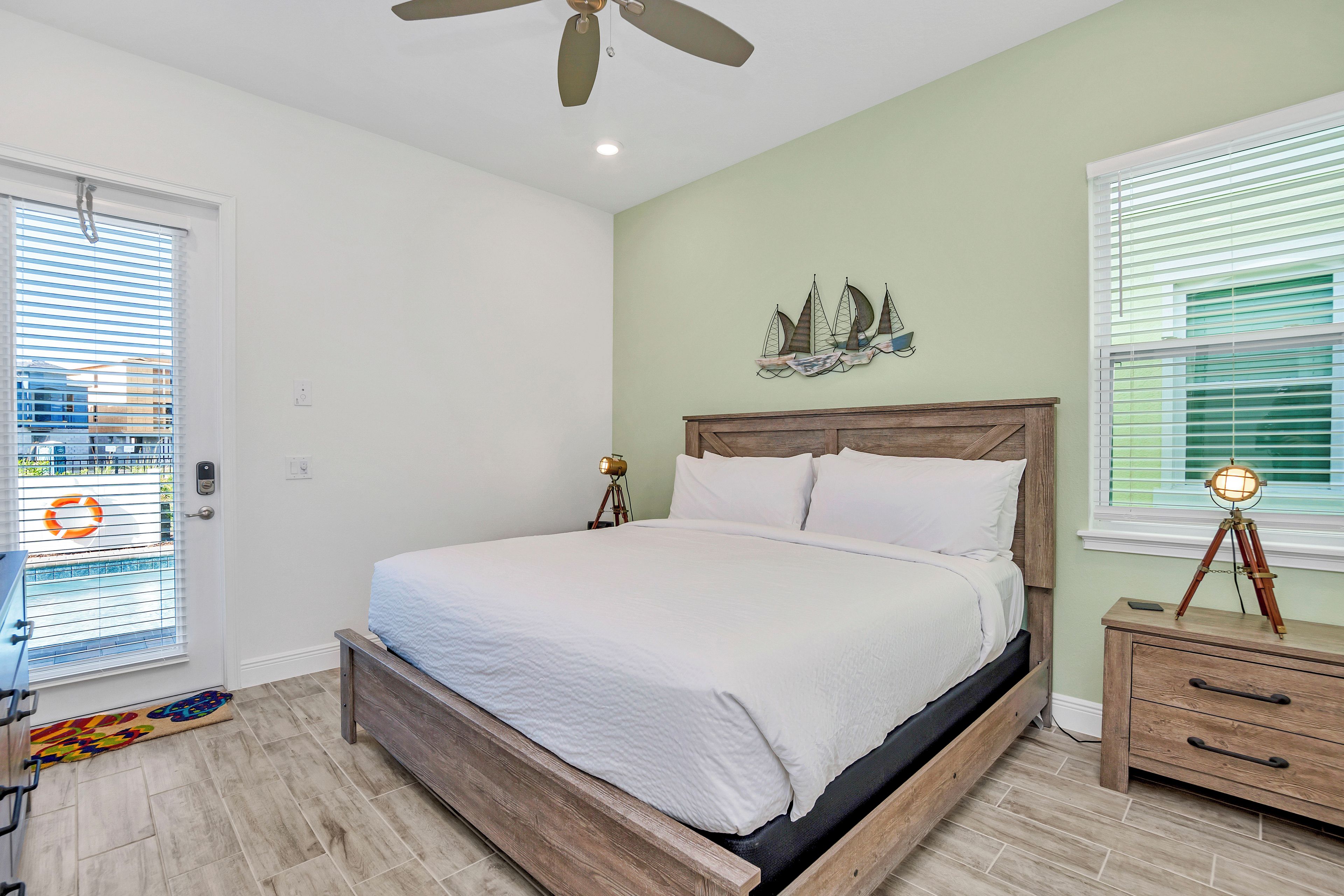 A bedroom with a bed, a nightstand, a ceiling fan, and a window with blinds.
