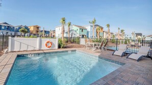 A swimming pool with lounge chairs and a lifebuoy, surrounded by a fence and palm trees. - Margaritaville Cottage, Private Pool, Near Disney! (Kissimmee)