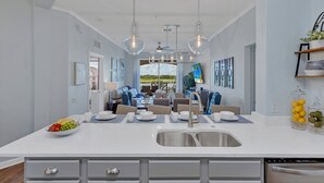 A modern kitchen with a central island, stainless steel appliances, and a dining area with a view of the outdoors.