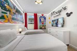 Ein Schlafzimmer im Mickey-Mouse-Design mit zwei Betten, einem Fernseher und einem Wandgemälde.
