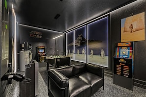 Ein Zimmer mit Fußballtisch, einer Couch, einer Star Wars-Dekoration und einem großen Fenster mit Blick auf eine Wüstenlandschaft.