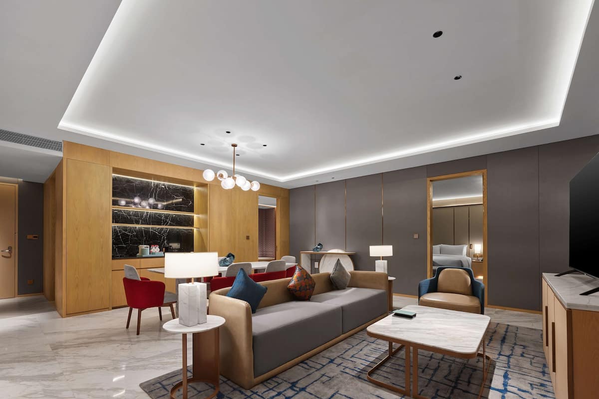 A modern living room with a sofa, red chairs, a coffee table, and a TV.