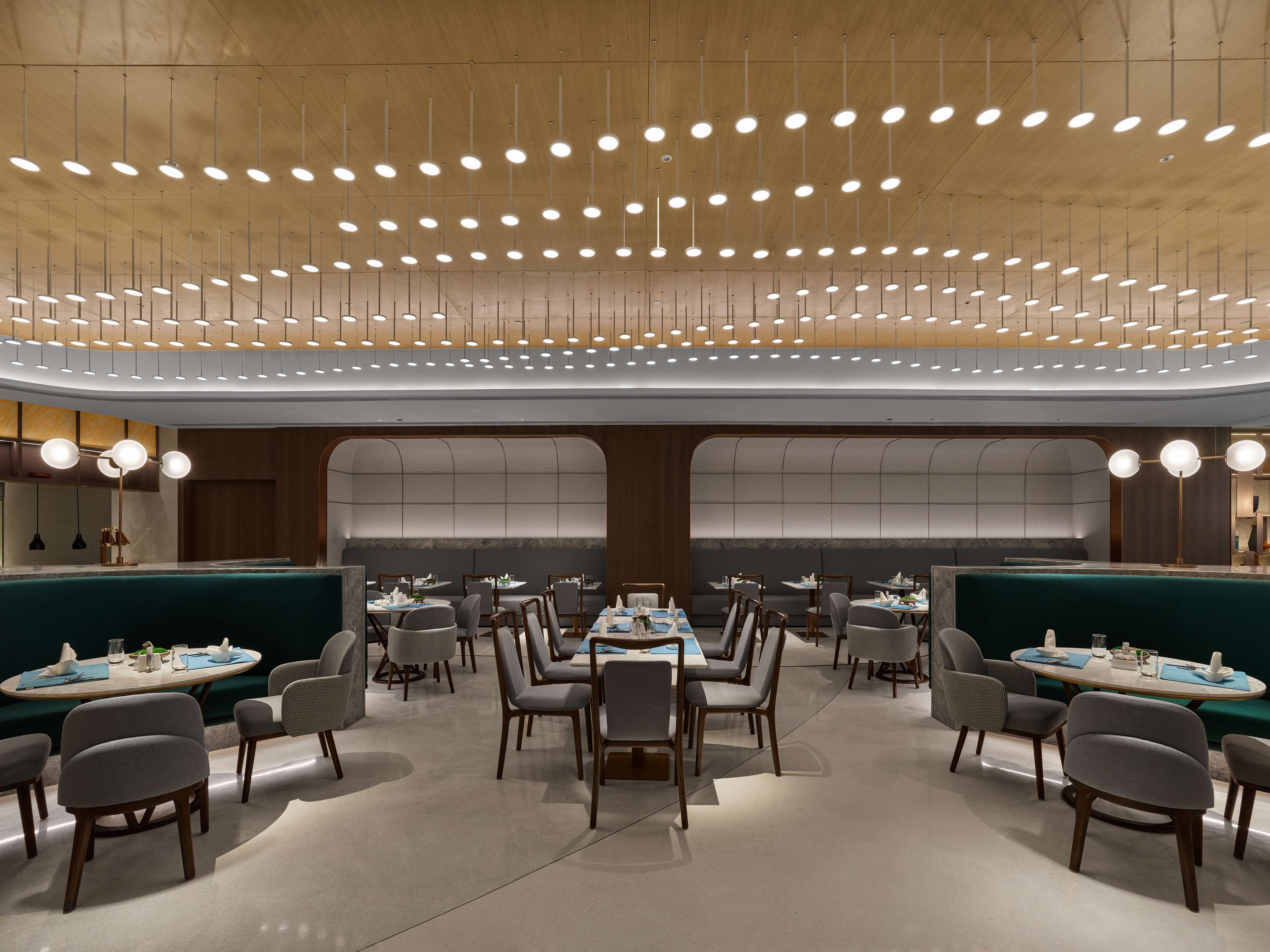 A modern restaurant with round tables, chairs, and a ceiling with hanging lights.