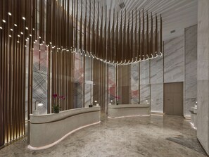 A modern reception area with vertical light fixtures, marble flooring, and a curved reception desk. - DoubleTree by Hilton Nanning Wuxiang (Nanning)