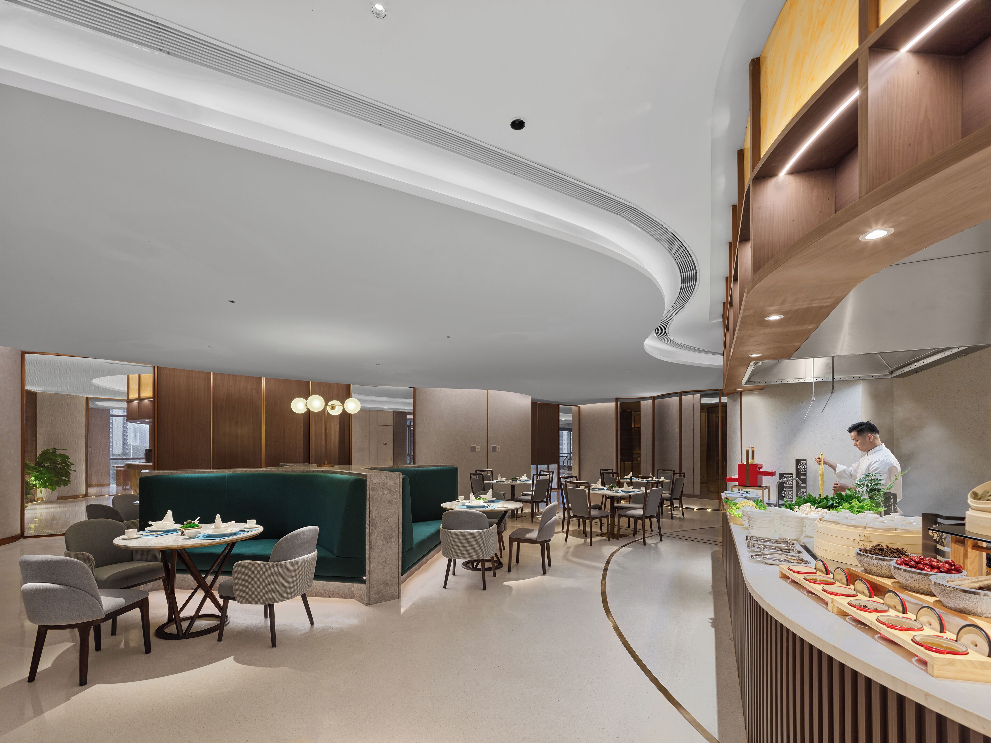 Un restaurante moderno con techo curvo, paneles de madera y un chef preparando comida.