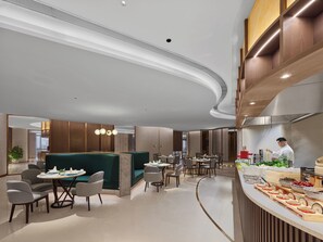 A modern restaurant with a curved ceiling, wooden paneling, and a chef preparing food. - DoubleTree by Hilton Nanning Wuxiang (Nanning)