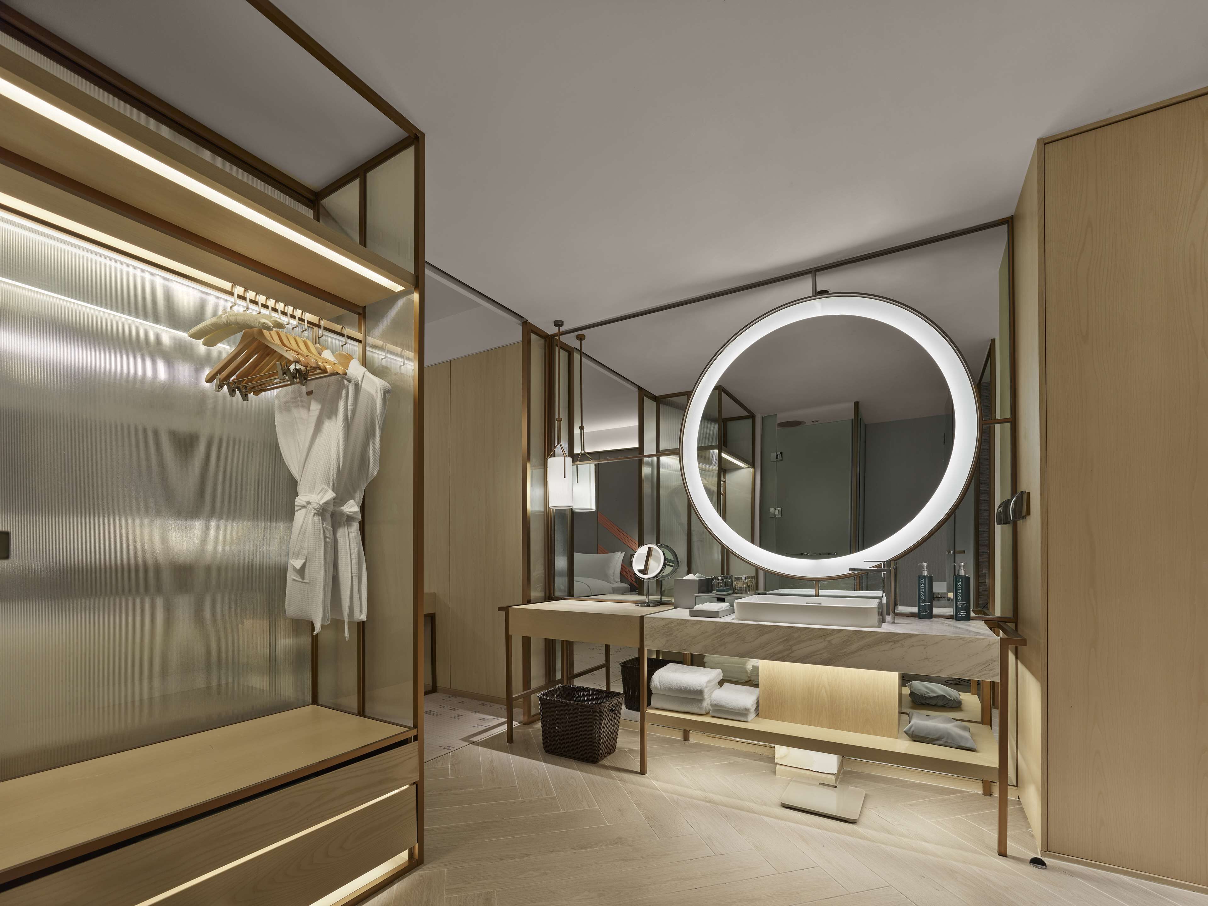 A modern bathroom with a vanity, a large mirror, and a robe rack.