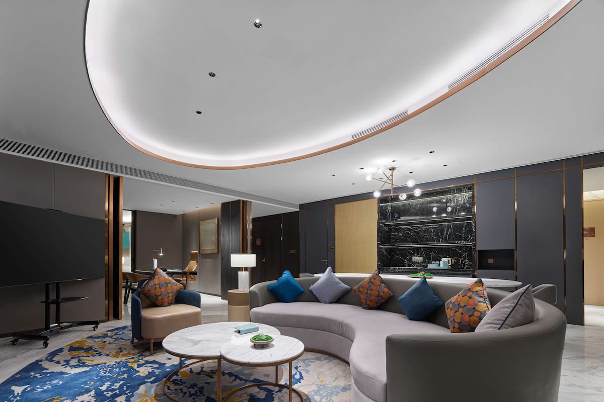 A modern living room with a curved sofa, a round coffee table, and a TV.
