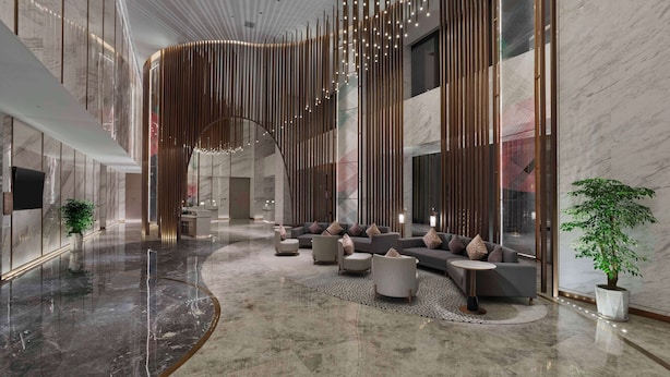 Um lobby moderno com piso de mármore curvo, áreas de estar e design de teto singular com luminárias pendentes.